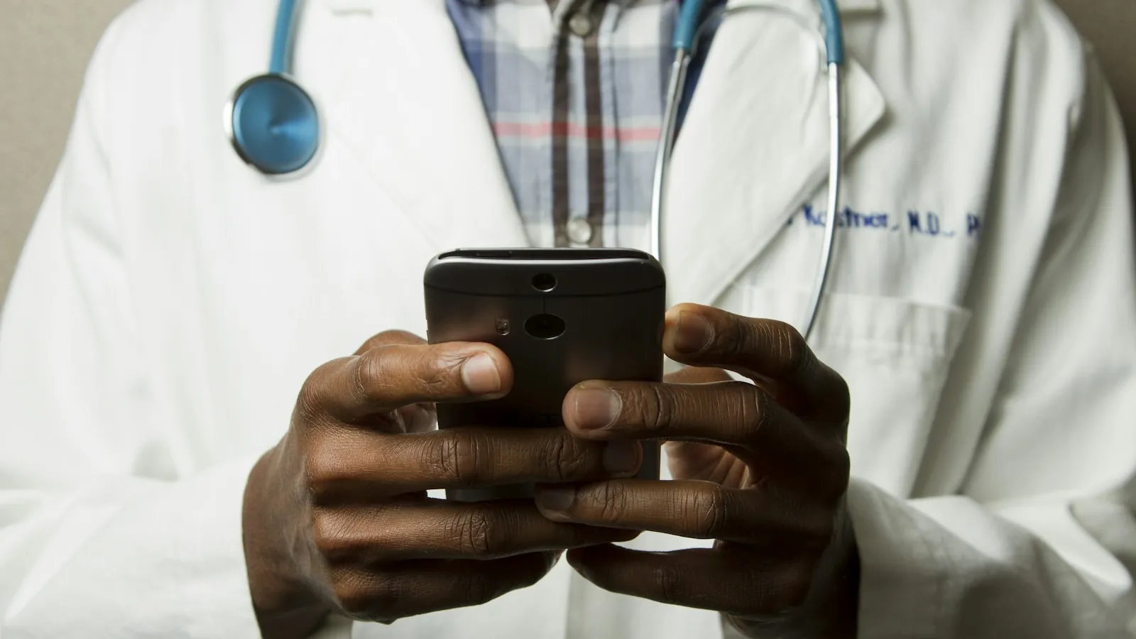 A doctor in a white coat using a phone